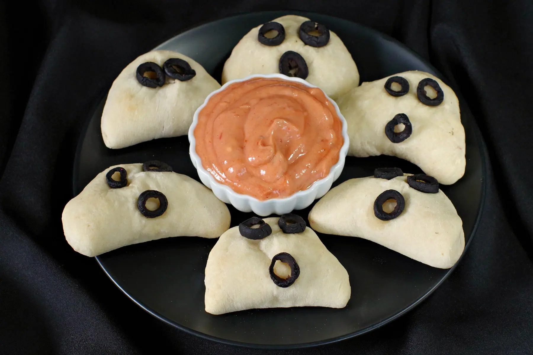 Halloween mini pizza pockets on a black plate with dip