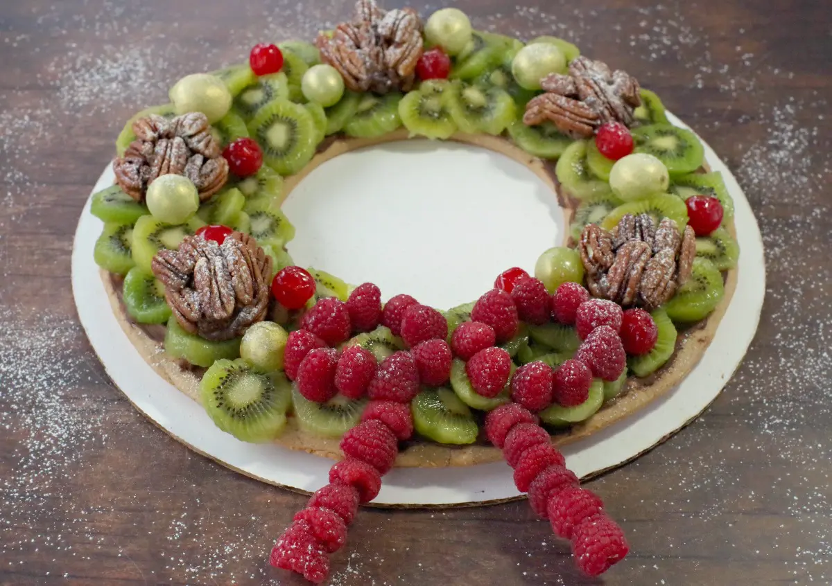 Edible Christmas Wreath made of gingerbread, fruits and nuts on a brown wooden surface
