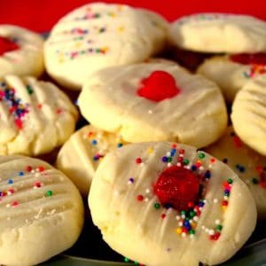 4 ingredient whipped shortbread piled on a plate with red background