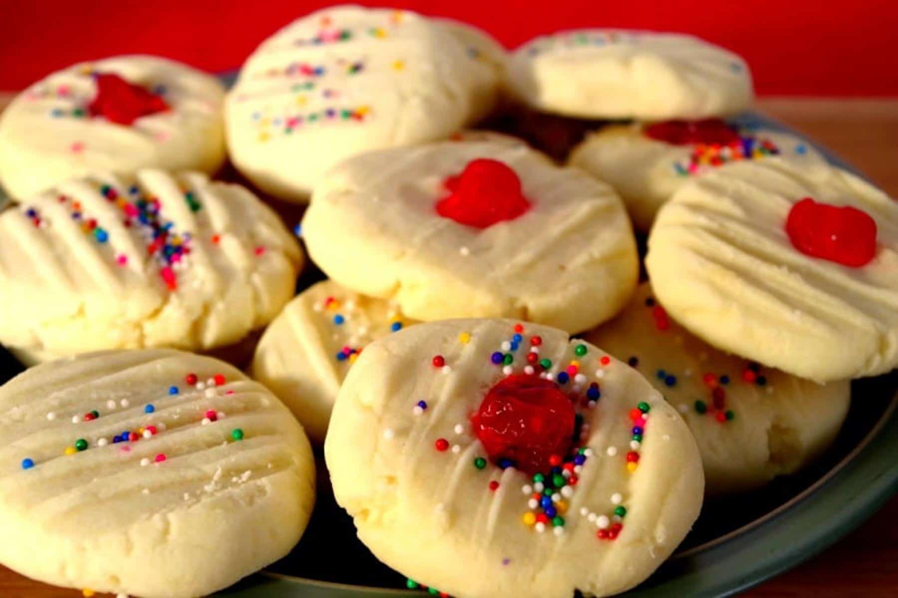 4 ingredient whipped shortbread piled on a plate with red background