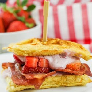 chicken and waffle sandwich with strawberries in background