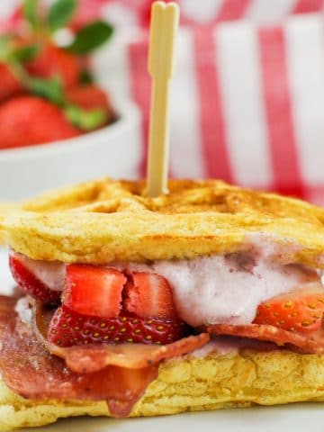 chicken and waffle sandwich with strawberries in background