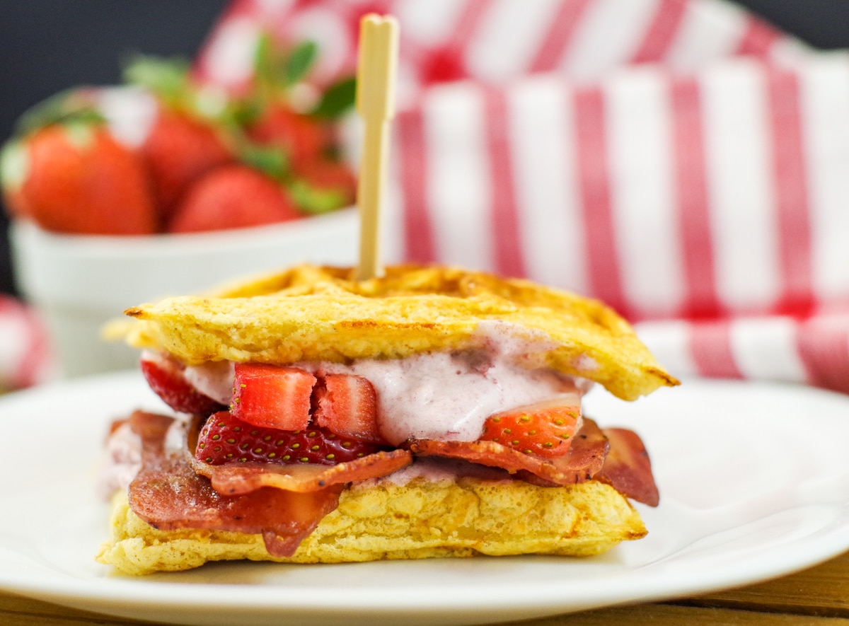 chicken and waffle sandwich with strawberries in background