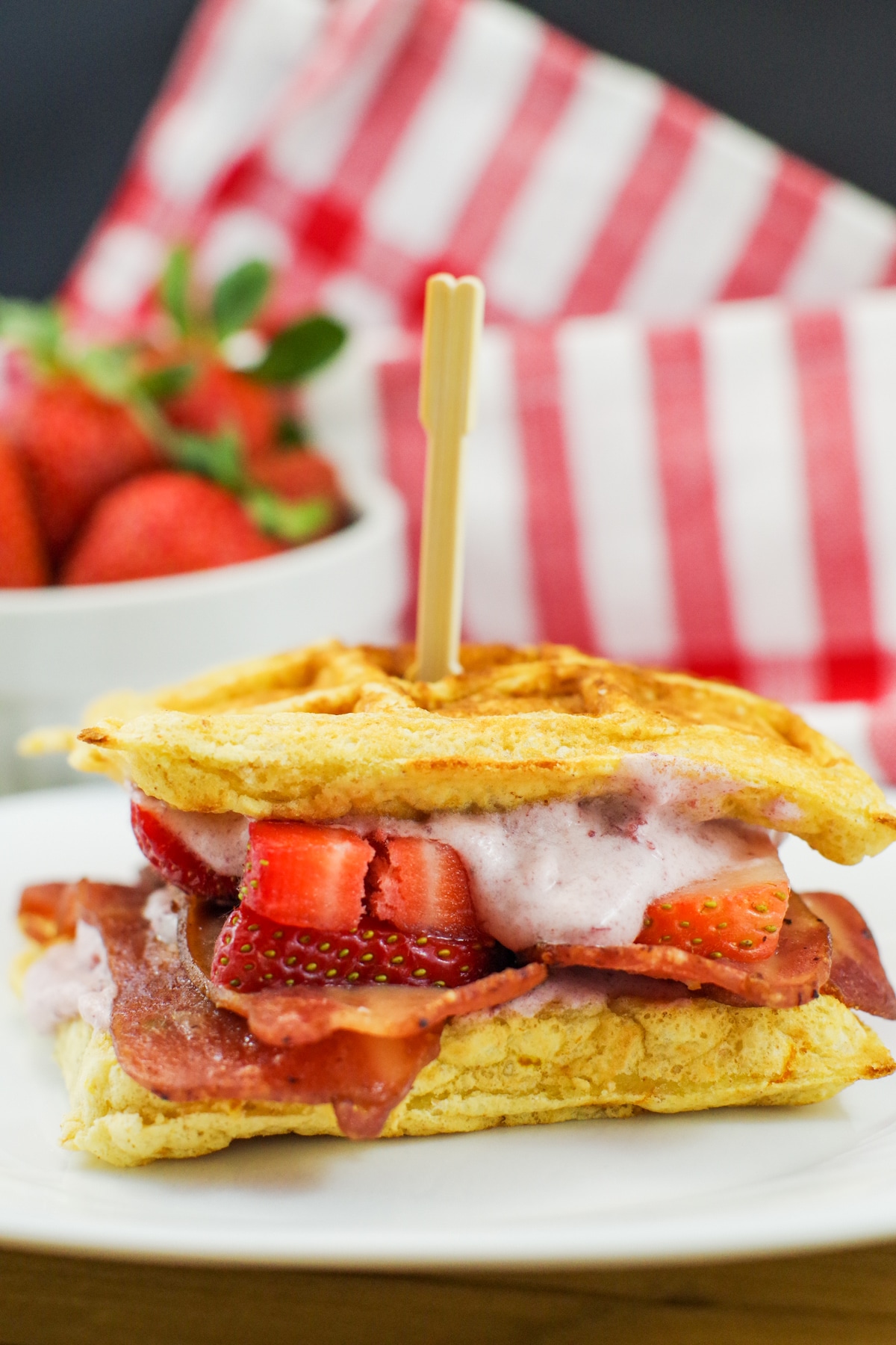 chicken and waffle sandwich with strawberries in background