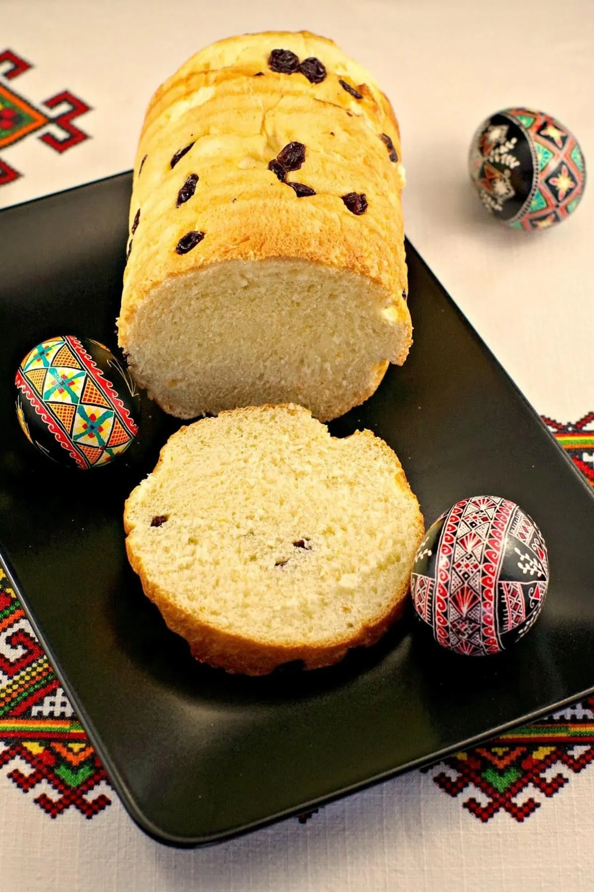 babka Ukrainian Easter bread on a black platter with Ukrainian Easter eggs around it