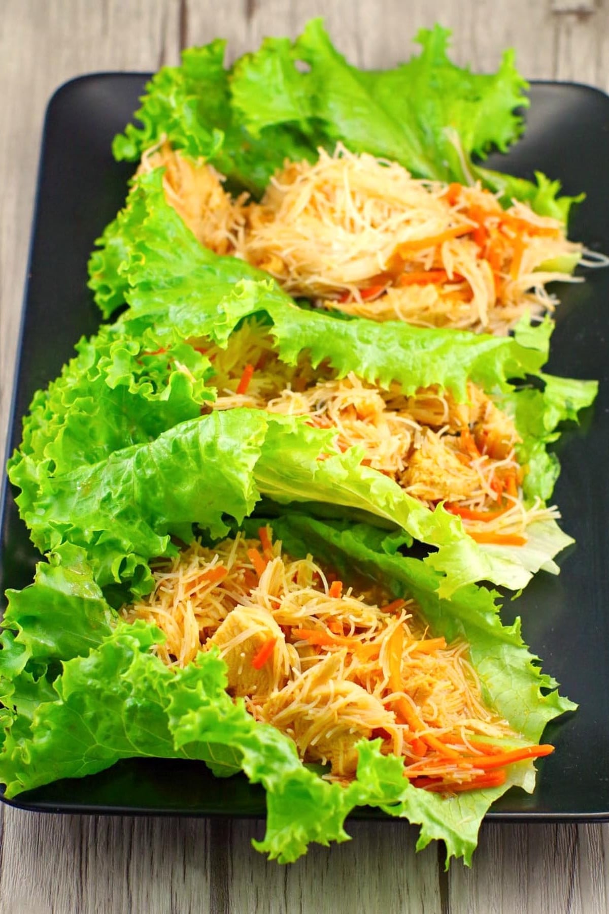 3 honey sriracha chicken lettuce wraps on a black platter