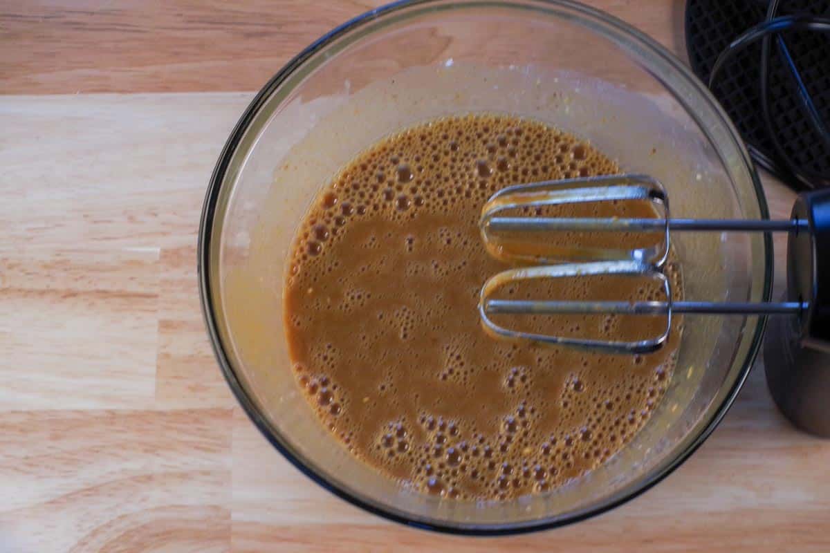 Ingredients beaten together in a large glass bowl, with beaters above the bowl