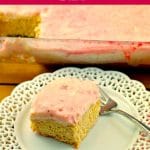 Strawberry blondie bar on a fancy white plate with whole clear casserole dish of blondies in backaground (with piece missing)