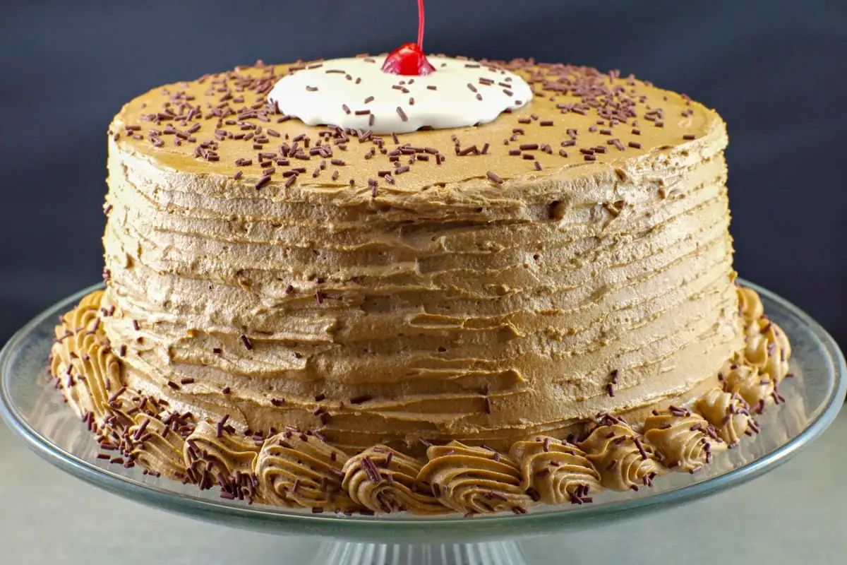 whole root beer float cake on a clear glass cake platter with black background