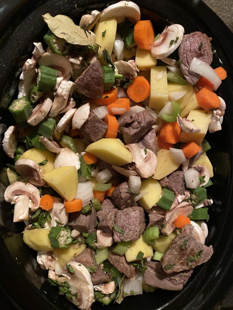meat, veggies an herbs in a slow cooker