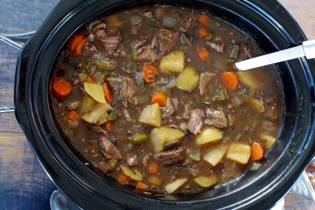 crockpot beef stew in a slow cooker with a ladle
