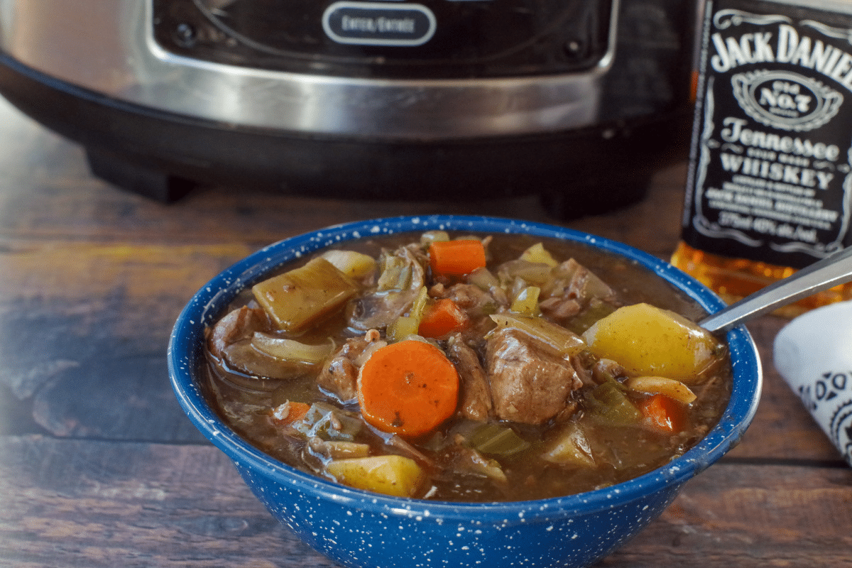 slow cooker beef stew in a blue bowl with slow cooker in the background