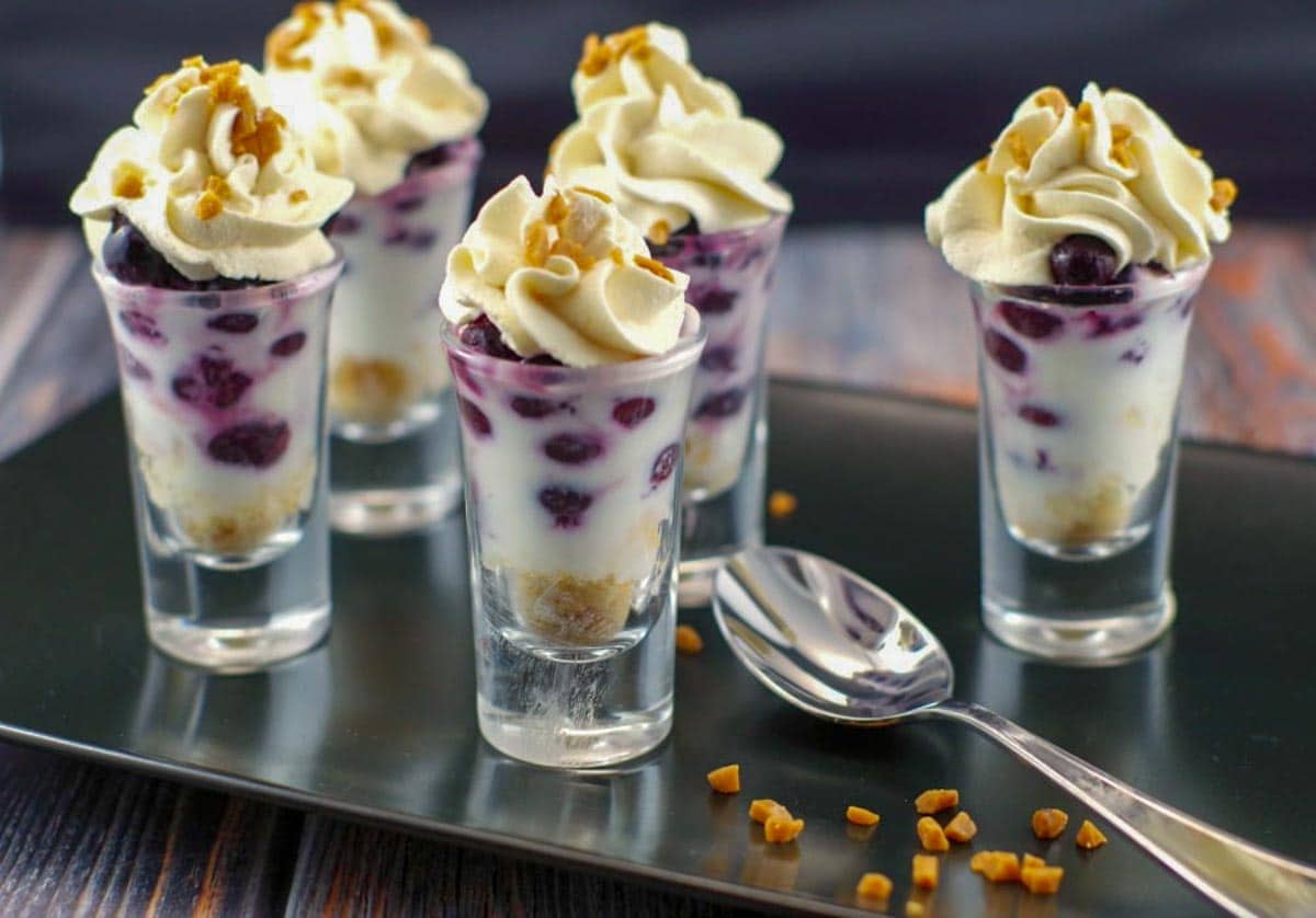 saskatoon berry dessert shooters on a black tray with a spoon