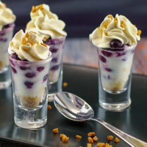 saskatoon berry dessert shooters on a black tray with a spoon