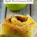 Bread Machine Apple Pie Cinnamon roll on a piece of parchment paper with a green apple and piece of gruyere cheese in the background.