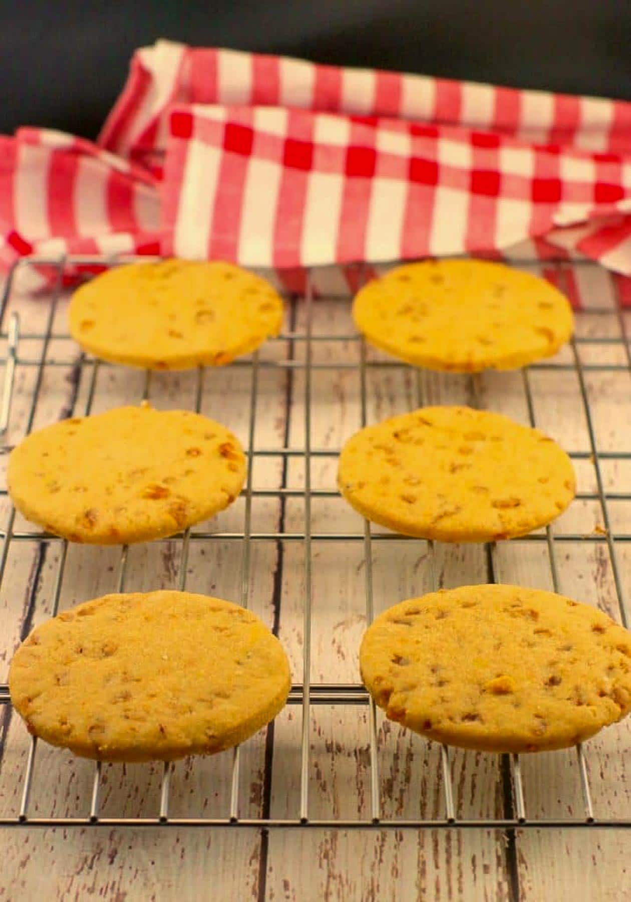 butterscotch toffee cookies on a wire cooling rack, with checkered red and white tablecloth