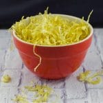 parsnip crisps/fried parsnips in an orange bowl on white surface