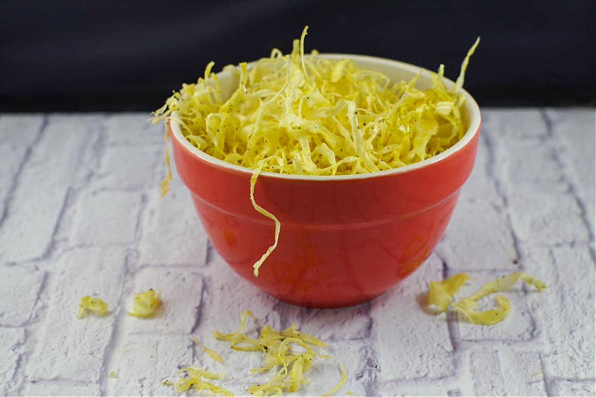parsnip crisps in an orange bowl on white surface