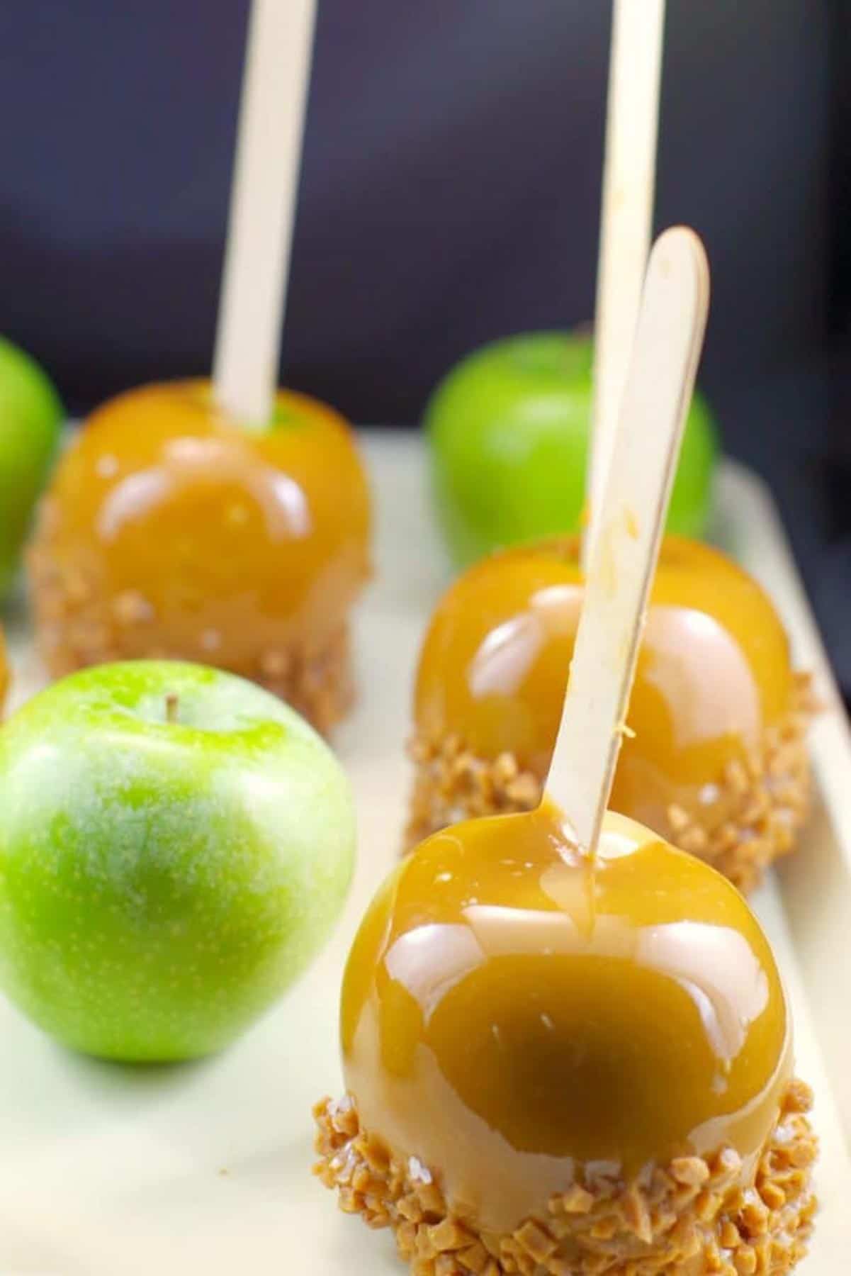 green and caramel apples on a beige tray