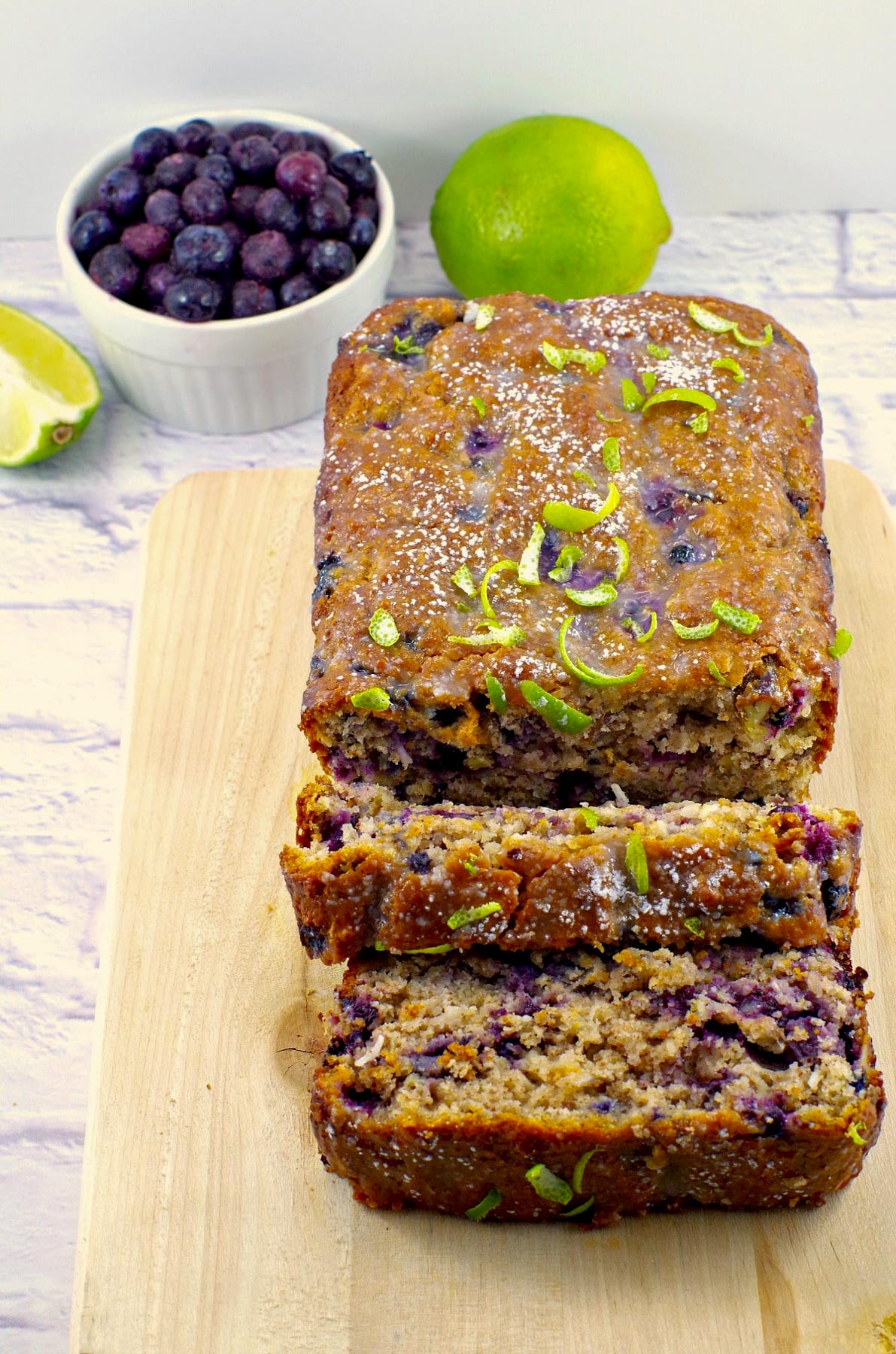 gingerbread loaf on a cutting board with blueberries and limes in background