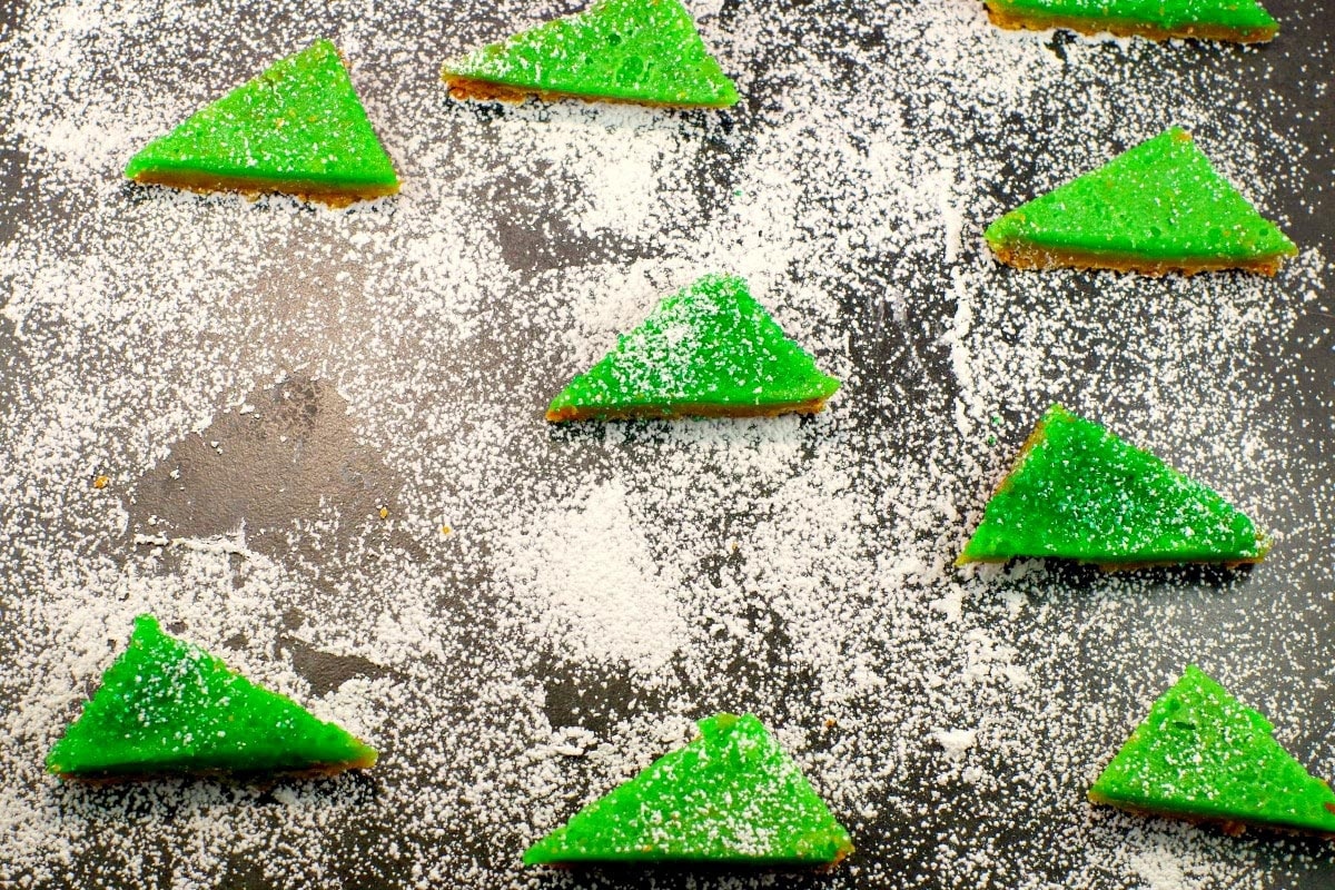 lime squares with powdered sugar on a cutting board with powdered sugar and space where one has been removed