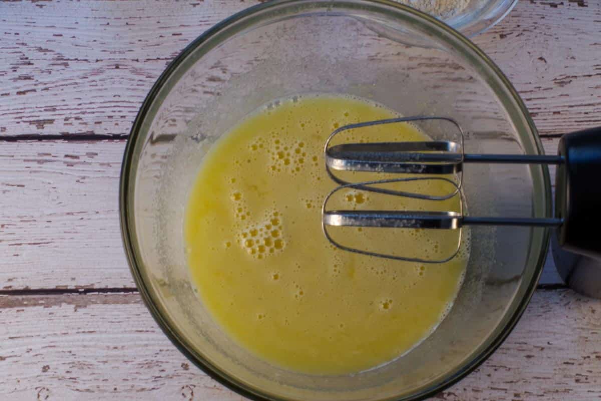 Eggs, lime juice and white sugar beaten together with an electric mixer, in a large glass bowl, with beaters over bowl.