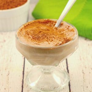 chocolate yogurt in a glass dessert dish with cocoa and green napkin in background