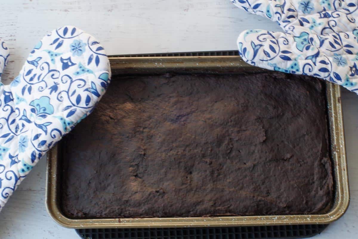 cooked brownies in pan with blue patterned oven mittes