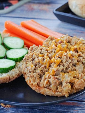 photo of weight watchers turkey sloppy joes on a black plate with carrots and cucumbers