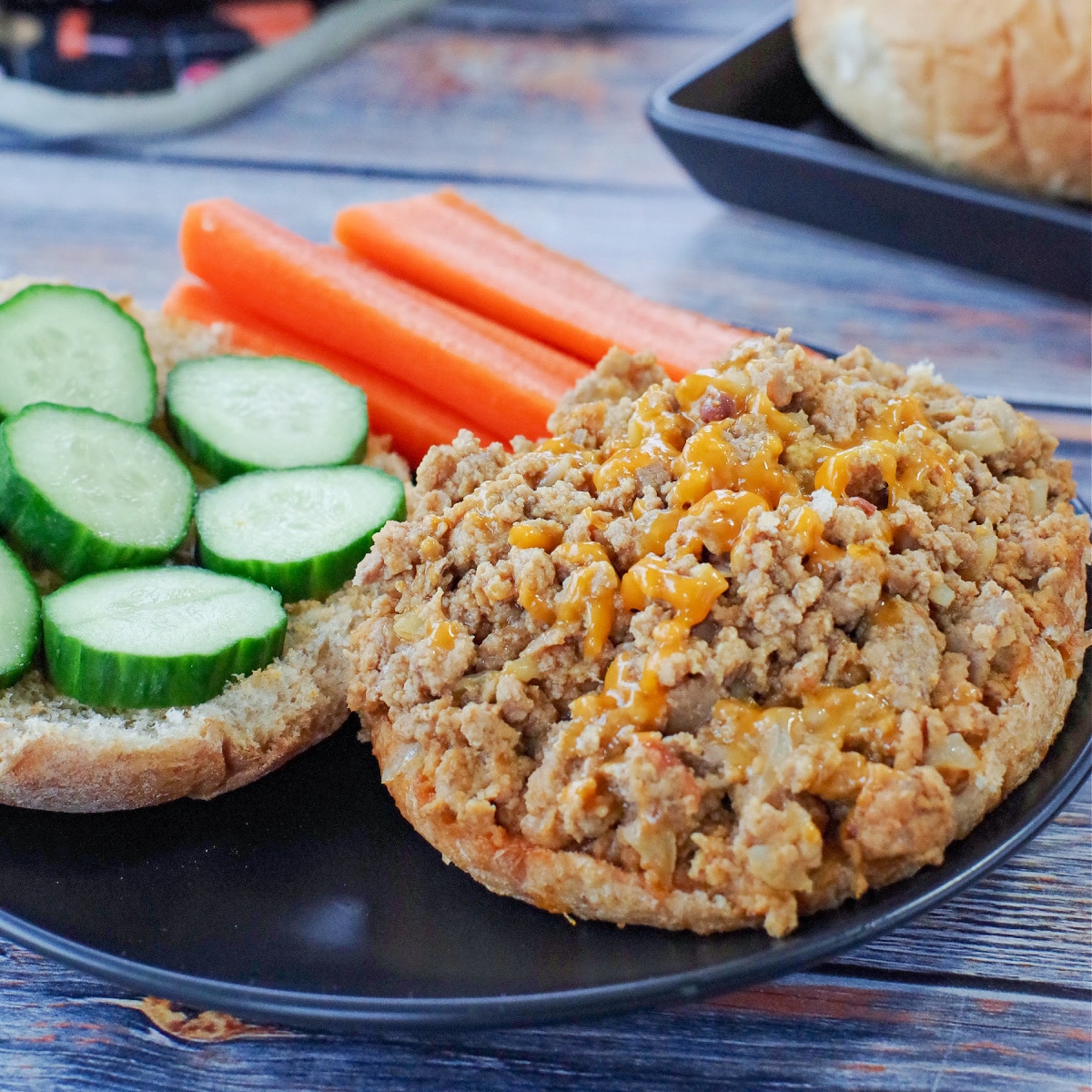 photo of weight watchers turkey sloppy joes on a black plate with carrots and cucumbers