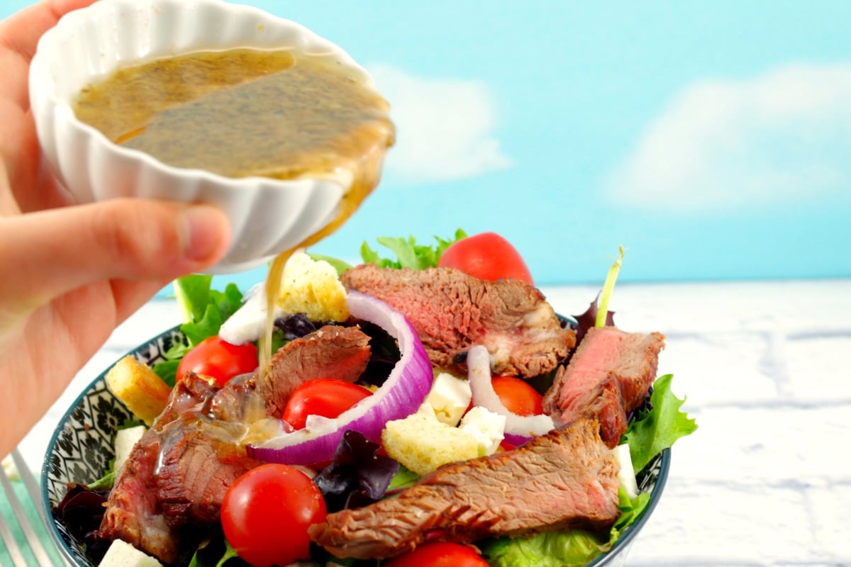 Moxie's Copycat Grilled Steak Salad with Clamato dressing being poured on top