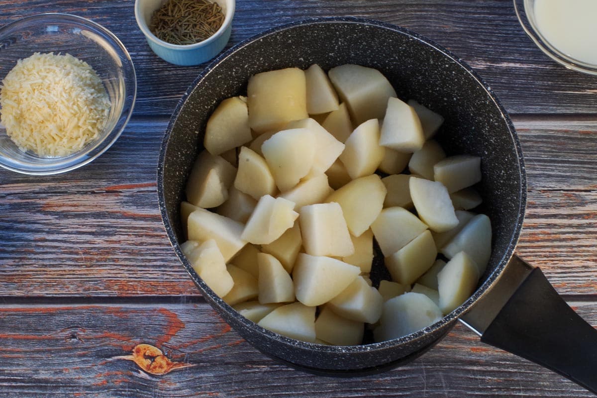 Chopped potatoes in a pot, cooked and drained.