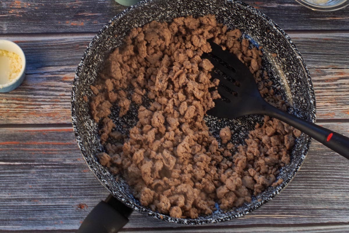 Cooked ground turkey in frying pan with spatula.