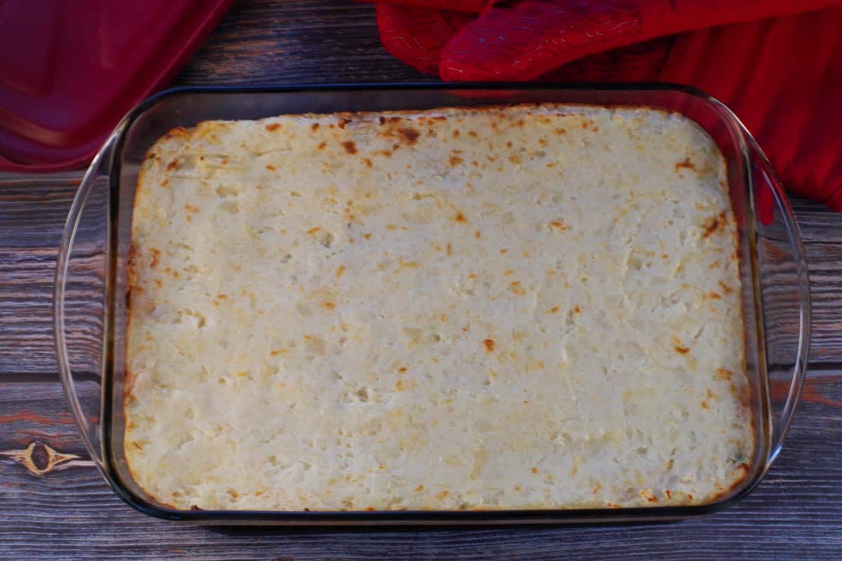 Baked Shepherd's Pie with ground turkey in a 9x13 glass casserole dish, with red oven mitts in the background.