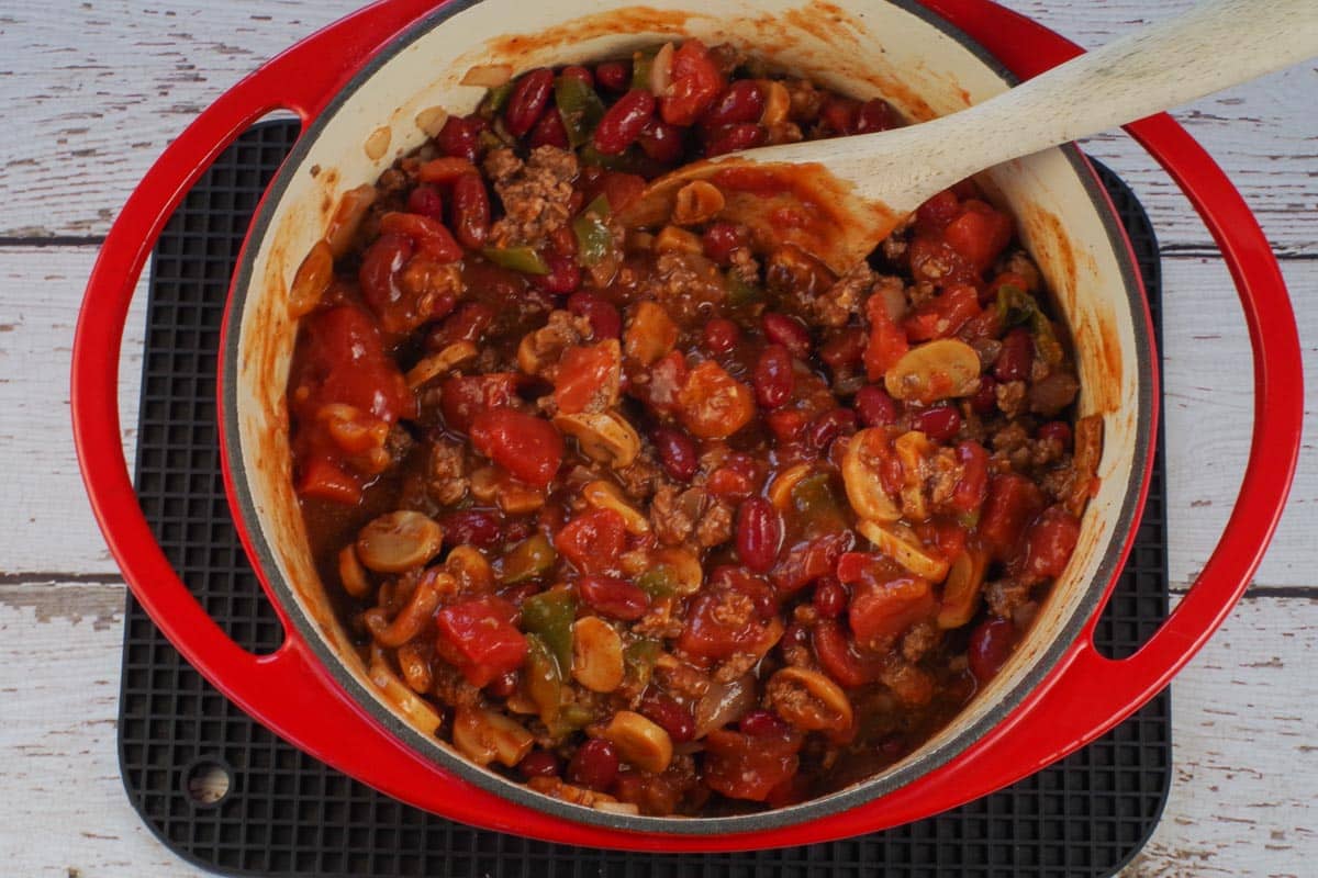 beef and pork with other chili ingredients besides dill and garnishes in orange dutch oven