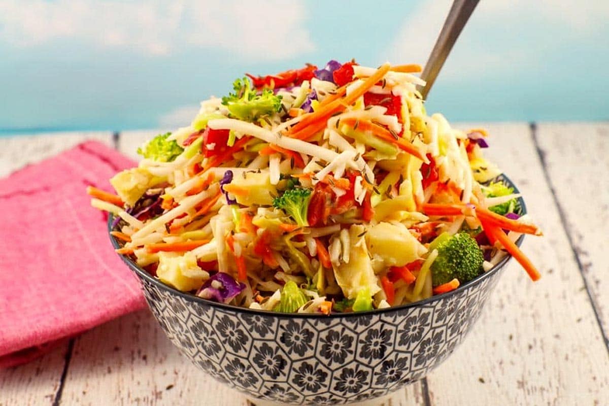 Healthy coleslaw in a black and white patterned bowl with a spoon sticking out of the coleslaw