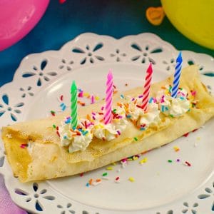Birthday Cake Batter and Ice Cream Crepes on a white plate with balloons in the background
