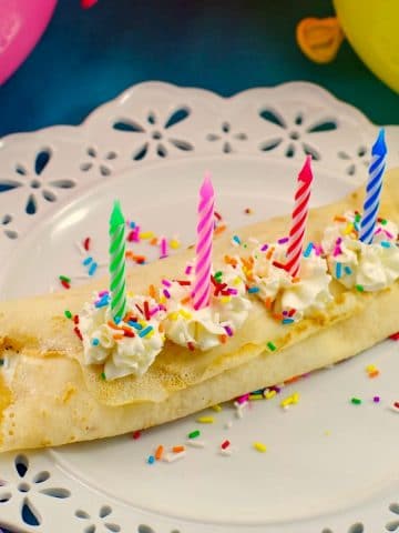 Birthday Cake Batter and Ice Cream Crepes on a white plate with balloons in the background