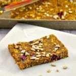 Healthy Fruit and Oat Bars on white plate with pan of more in the background