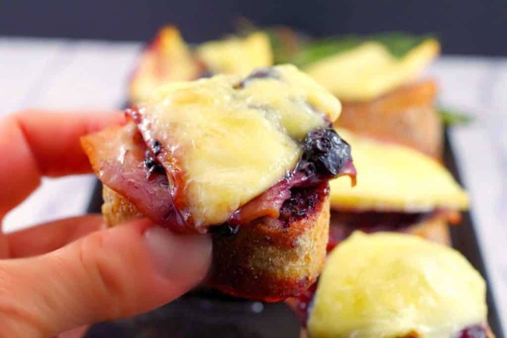 turkey brie bite being held up over a tray of more turkey brie bites