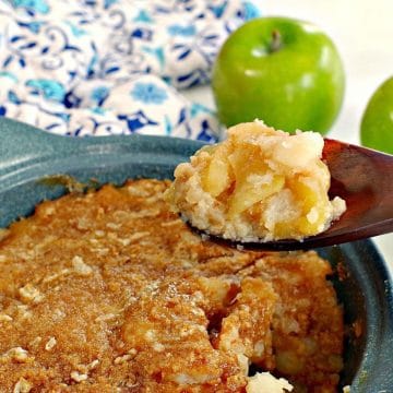turnip and apple casserole (weight watchers friendly in a blue casserole dish, being held up on a wooden spoon with a green apple and blue patterned oven mitt in the background