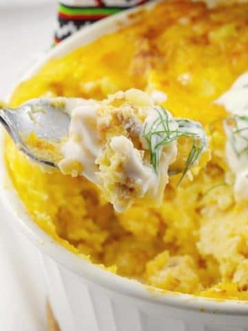 frozen perogy breakfast casserole om a white casserole dish, with a spoonful being held up