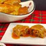 ground beef and rice cabbage rolls cut open on a white plate with plate of cabbage rolls in the background on tartan print tablecloth