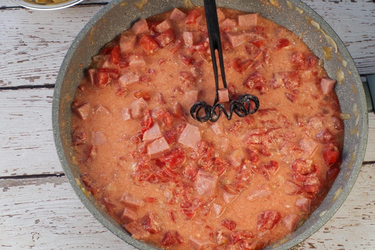 Mascarpone cheese whisked into ham mixture in large skillet with black whisk