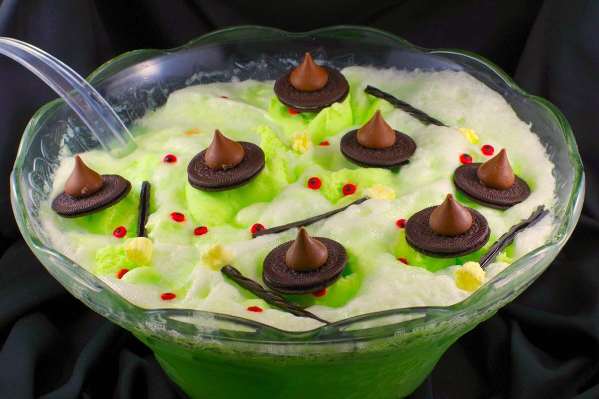 Melting witch green Halloween punch with chocolate hats, licorice marshmallow brooms and candy eyes