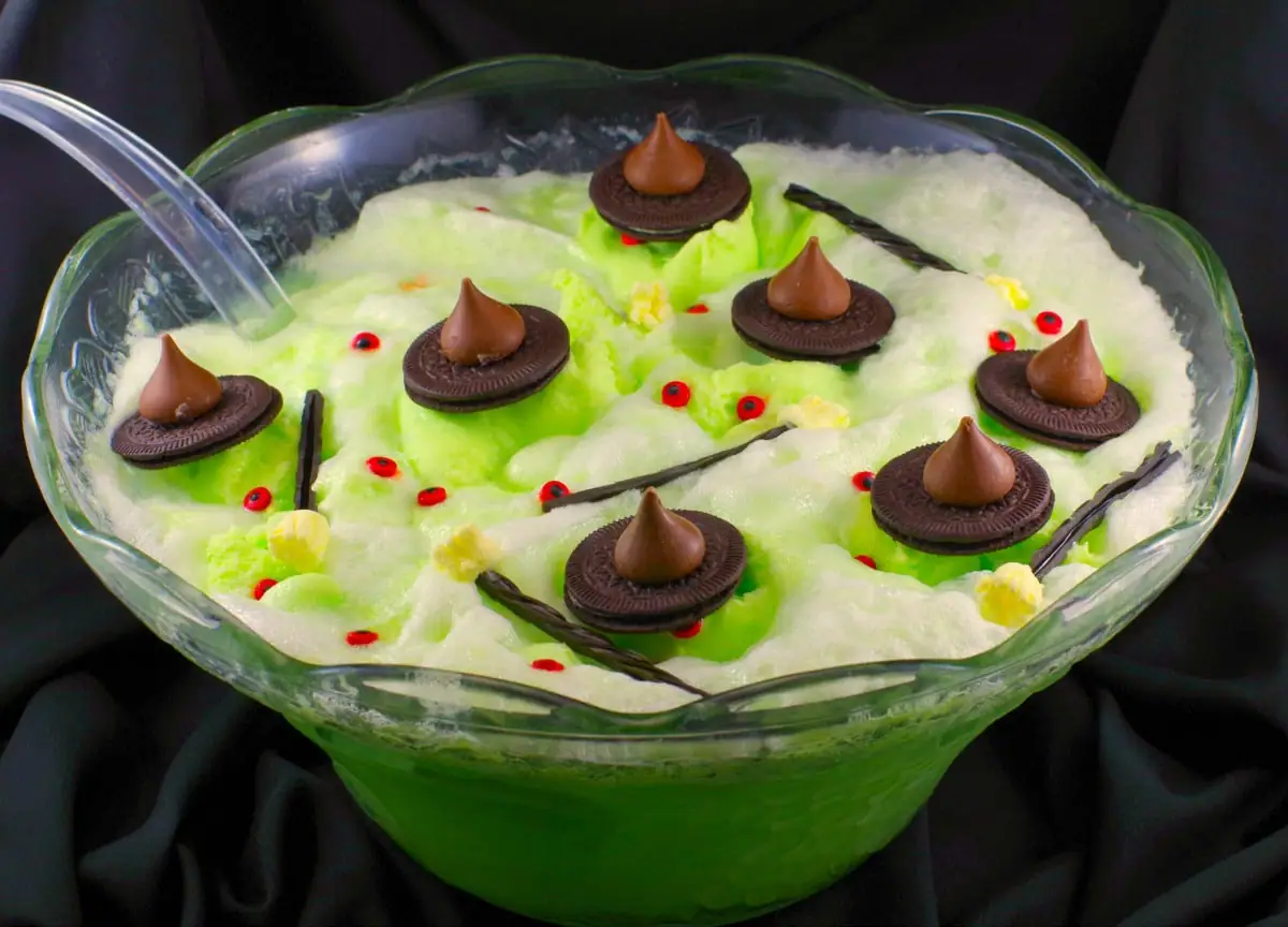Melting witch green Halloween punch with chocolate hats, licorice marshmallow brooms and candy eyes
