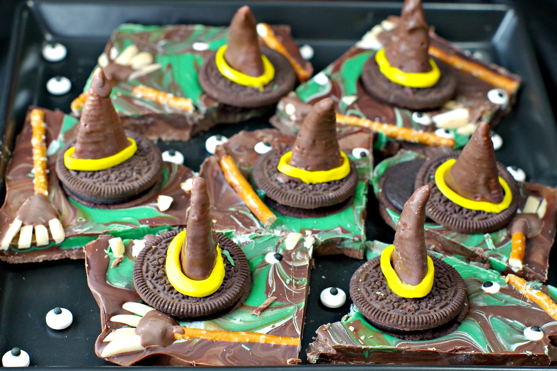 Melting Witch Halloween Chocolate Bark broken into pieces on black platter with extra candy eyes scattered on plate