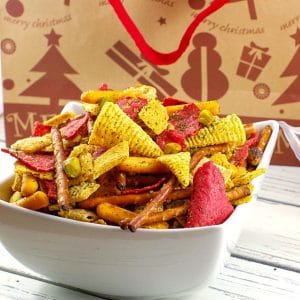 Christmas Chex Mix in a white bowl with a festive Christmas bag in the background