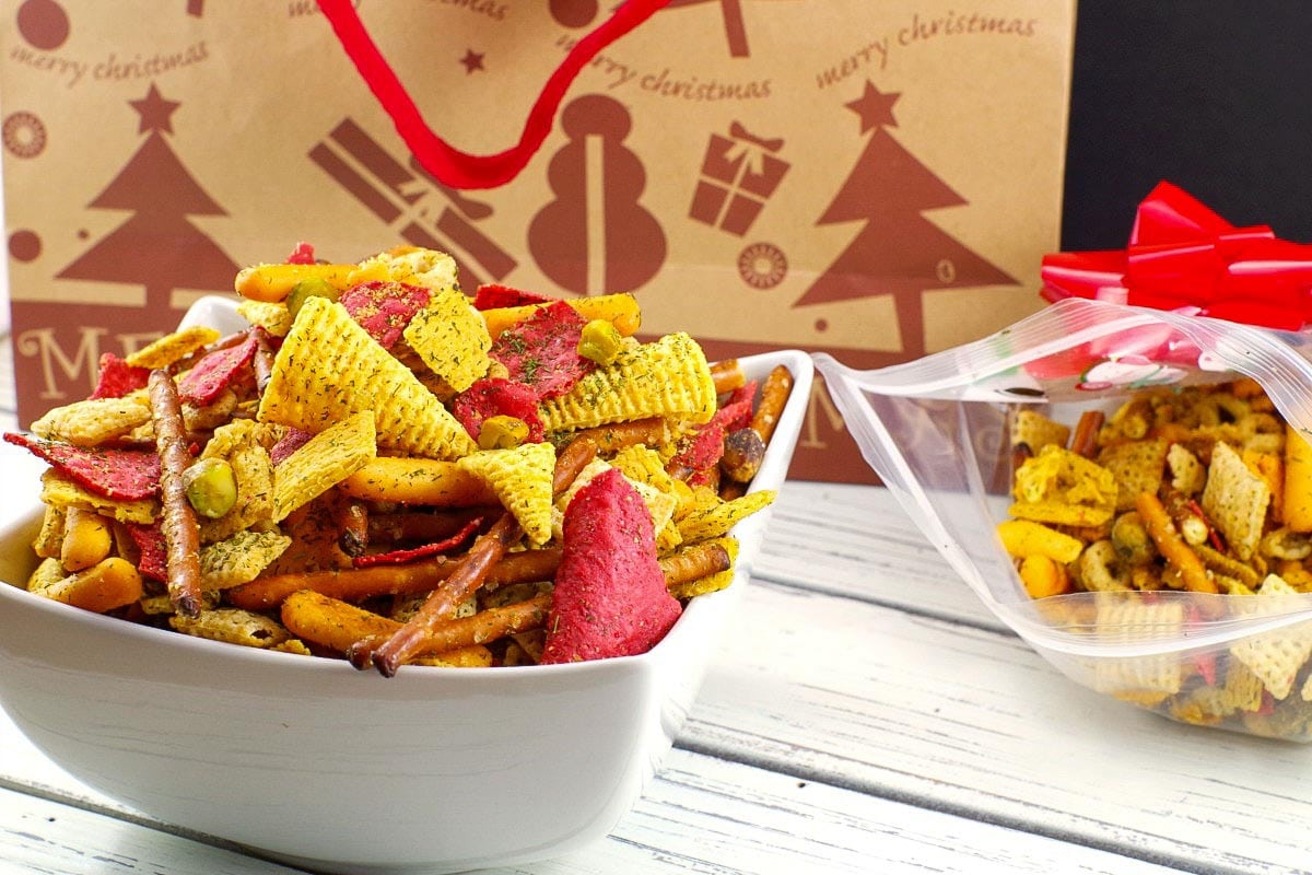 Christmas Chex Mix in a white bowl with a festive Christmas bag in the background