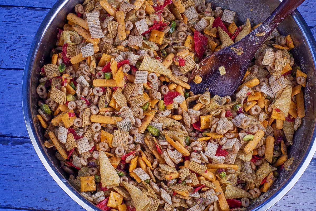 Butter mixture poured into cereal mixture and stirred, in large stainless steel bowl, with wooden spoon.